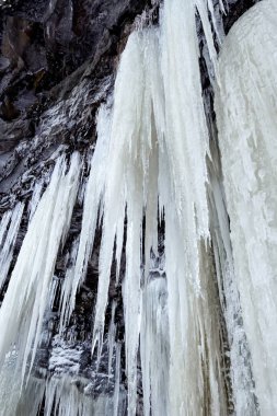 Manzaralı kış manzarası, donmuş şelalelerin çağlayanı kayalardan yere kadar sarkan devasa uzun buz saçakları. Babcock düşüyor, Tumbler Tepesi, BC, Kanada