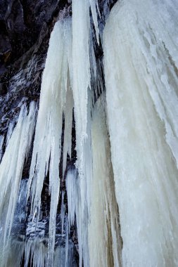 Manzaralı kış manzarası, donmuş şelalelerin çağlayanı kayalardan yere kadar sarkan devasa uzun buz saçakları. Babcock düşüyor, Tumbler Tepesi, BC, Kanada