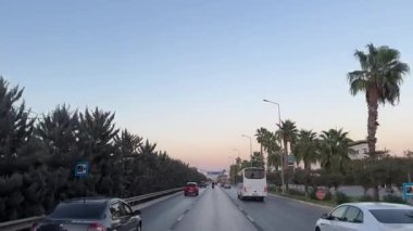 Kemer, Türkiye - 24 Eylül 2025: Gün batımında palmiye çizgili otoyolun sürekli görüntüsü, kamera araçları ilerlerken takip ediyor, canlı renkler ve hareketler yakalıyor