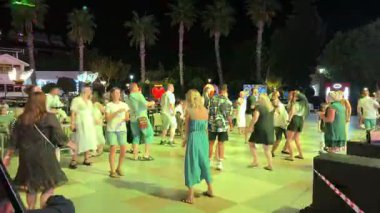 Kemer, Turkey - September 20, 2025: Ballon party. Dynamic outdoor dance party with lively crowd under palm trees, camera smoothly pans to capture joyful atmosphere