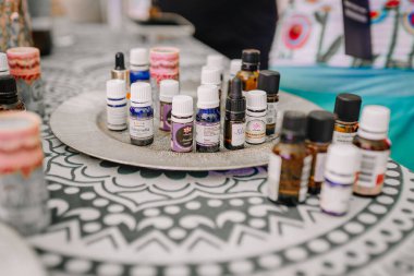 Saldus, Latvia - July 19, 2025 - Various essential oil bottles displayed on a decorative tray at an outdoor market or wellness event. The bottles are labeled with names like citronella and lavender.