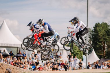 Valmiera, Letonya - 12 Temmuz 2025: BMX Avrupa Şampiyonası. BMX yarışçıları heyecan verici bir yarışmada havada süzülüyor. Seyirciler izliyor.