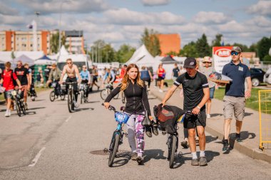 Valmiera, Letonya - 12 Temmuz 2025: BMX Avrupa Şampiyonası. Beyaz kadın ve erkek, canlı açık havada bisikletle çadır kurarak bisiklete biniyorlar.