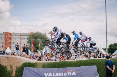 Valmiera, Letonya - 12 Temmuz 2025: BMX Avrupa Şampiyonası. BMX sürücüleri coşkulu seyircilerle yarışarak hava taktikleri uyguluyorlar.