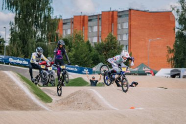 Valmiera, Letonya - 12 Temmuz 2025: BMX Avrupa Şampiyonası. Rekabetçi BMX yarışçıları yakınlardaki izleyicilerle toprak rampalarda sıçrama yapıyorlar.