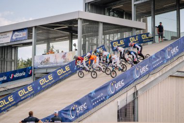 Valmiera, Letonya - 12 Temmuz 2025: BMX Avrupa Şampiyonası. BMX yarışçıları, izleyicilerin izlediği bir bisiklet yarışında rampadan fırlatılıyor.