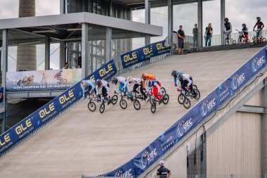 Valmiera, Letonya - 12 Temmuz 2025: BMX sürücüleri bir şampiyonluk yarışında seyircilerin izlediği dik bir rampada yarışıyorlar. BMX Avrupa Şampiyonası