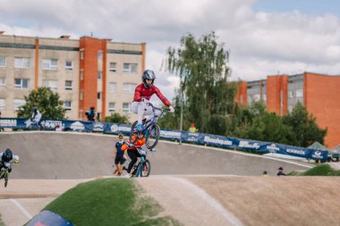 Valmiera, Letonya - 12 Temmuz 2025: BMX atleti arka planda şehir binaları ve izleyicilerle pistte bir atlayış gerçekleştiriyor. BMX Avrupa Şampiyonası