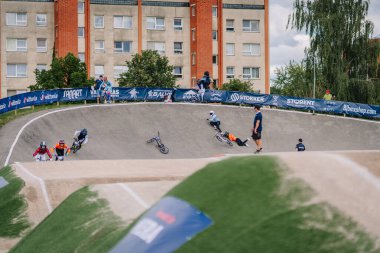 Valmiera, Letonya - 12 Temmuz 2025: Genç BMX sürücüleri şehir ortamında saha kenarından izleyen seyircilerle yarış halindeler. BMX Avrupa Şampiyonası