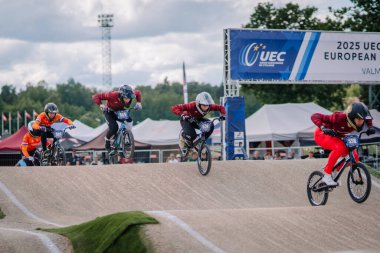 Valmiera, Letonya - 12 Temmuz 2025: BMX yarışçıları, 2025 UEC Avrupa Şampiyonası 'nda arkasında coşkulu bir kalabalık ile şiddetle yarışıyorlar. BMX Avrupa Şampiyonası