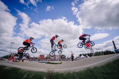 Valmiera, Letonya - 12 Temmuz 2025: BMX atletleri bulutlu bir gökyüzü altında yapılan yarışma sırasında hava taktiklerini uyguluyorlar. BMX Avrupa Şampiyonası