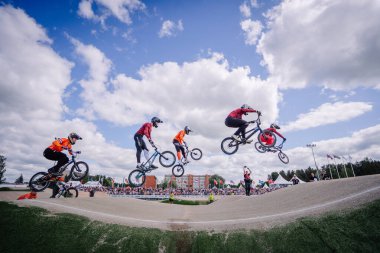 Valmiera, Letonya - 12 Temmuz 2025: BMX atletleri, yakınlardaki coşkulu izleyicilerin izlediği bir yarışma sırasında hava hilelerini uyguluyorlar. BMX Avrupa Şampiyonası