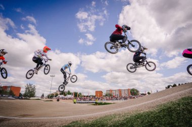 Valmiera, Letonya - 12 Temmuz 2025: BMX atletleri izleyicilerin izlediği heyecan verici bir yarışma sırasında etkileyici hava numaraları sergiliyorlar. BMX Avrupa Şampiyonası