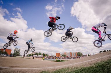 Valmiera, Letonya - 12 Temmuz 2025: BMX sporcuları, arka planda izleyicilerin izlediği bir yarışma sırasında hava taktikleri uyguluyorlar. BMX Avrupa Şampiyonası