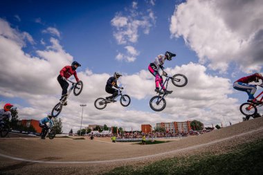 Valmiera, Letonya - 12 Temmuz 2025: BMX atletleri arka planda izleyen bir kalabalıkla yapılan bir yarışma sırasında hava taktikleri uyguluyorlar. BMX Avrupa Şampiyonası