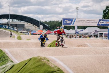 Valmiera, Letonya - 12 Temmuz 2025: Genç yarışmacılar 2023 UEC BMX Avrupa Yarışları sırasında toprak pistte BMX motorlarıyla yarışıyorlar