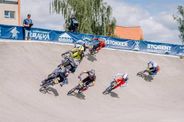 Valmiera, Letonya - 12 Temmuz 2025: BMX yarışçıları arka planda renkli afişler ve izleyicilerle pistte yarışıyor. BMX Avrupa Şampiyonası
