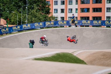 Valmiera, Letonya - 12 Temmuz 2025: BMX Avrupa Şampiyonası. BMX yarışçıları şehir binalarının arkasında yarış pistinde yeteneklerini sergiliyorlar.