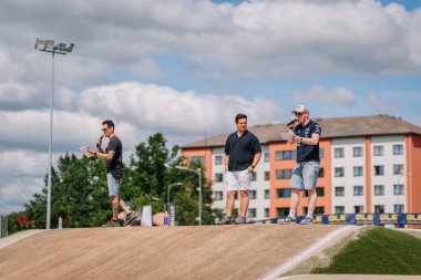 Valmiera, Letonya - 12 Temmuz 2025: BMX Avrupa Şampiyonası. BMX yarış pistinde ağaçlarla sohbet eden üç adamdan oluşan bir grup.