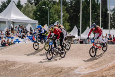 Valmiera, Letonya - 12 Temmuz 2025: BMX Avrupa Şampiyonası. Genç yarışçılar BMX motosikletleriyle toprak pistte yarışıyorlar ve yakınlarda seyirciler var.