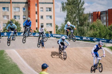 Valmiera, Letonya - 12 Temmuz 2025: BMX Avrupa Şampiyonası. BMX sürücüleri, toprak pistte seyircilerle yarışırken hava hileleri sergiliyorlar.