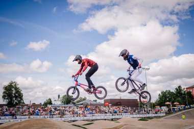 Valmiera, Letonya - 12 Temmuz 2025: BMX Avrupa Şampiyonası. BMX pistinde izleyicilerle yapılan yarış sırasında havada süzülen erkek BMX sürücüleri.