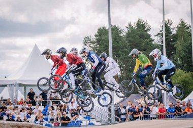 Valmiera, Letonya - 12 Temmuz 2025: BMX Avrupa Şampiyonası. Bir grup BMX sürücüsü, izleyicilerle dolu heyecanlı bir yarış sırasında rampadan atlıyorlar.