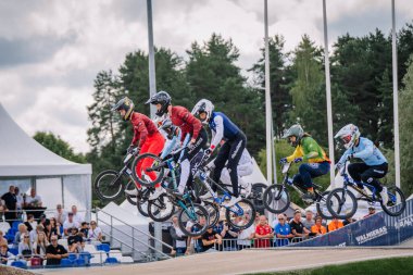 Valmiera, Letonya - 12 Temmuz 2025: BMX Avrupa Şampiyonası. Bir grup BMX yarışçısı, taraftarların izlediği bir yarışmada rampadan atlıyor.