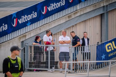 Valmiera, Letonya - 12 Temmuz 2025: BMX Avrupa Şampiyonası. Bir spor salonundaki çitlerin yanında markalı bir grup insan konuşuyor.