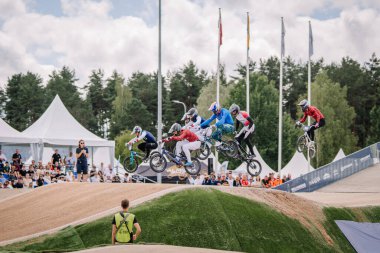 Valmiera, Letonya - 12 Temmuz 2025: BMX Avrupa Şampiyonası. Bir grup BMX sürücüsü, hayranlarının izlediği bir yarışmada hava taktikleri uyguluyor.