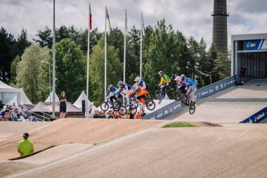 Valmiera, Letonya - 12 Temmuz 2025: BMX Avrupa Şampiyonası. Çok sayıda sürücünün temiz gökyüzünün altında toprak yolda uçtuğu heyecan verici bir BMX yarışı