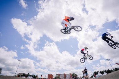 Valmiera, Letonya - 12 Temmuz 2025: BMX Avrupa Şampiyonası. BMX sürücüleri havada süzülüyor yarışma sırasında yukarıdaki canlı bulutlarla