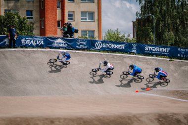 Valmiera, Letonya - 12 Temmuz 2025: BMX Avrupa Şampiyonası. BMX sürücüleri renkli pankartlar ve coşkulu izleyicilerle eğimli bir pistte yarışıyorlar