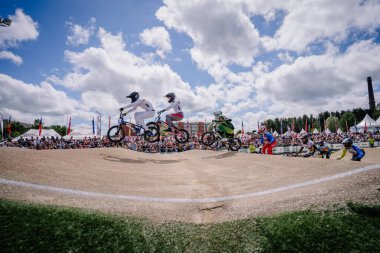 Valmiera, Letonya - 12 Temmuz 2025: BMX Avrupa Şampiyonası. BMX yarışçıları coşkulu bir kalabalık eşliğinde havada süzülüyor.
