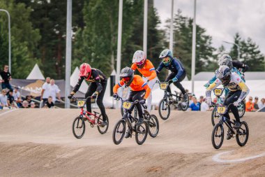 Valmiera, Letonya - 12 Temmuz 2025: BMX Avrupa Şampiyonası. Rekabetçi BMX yarışçıları toprak yolda seyircilerle heyecan verici yarışı izliyorlar.