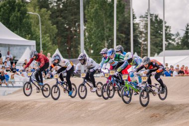 Valmiera, Letonya - 12 Temmuz 2025: BMX Avrupa Şampiyonası. Heyecan verici BMX yarışı. Toprak pistte birden fazla yarışçı var ve arkasında tezahürat yapan kalabalık var.
