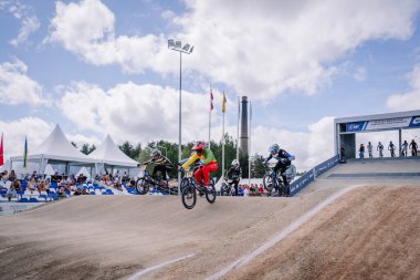 Valmiera, Letonya - 12 Temmuz 2025: BMX Avrupa Şampiyonası. Canlı vitesli BMX yarışçıları toprak pistte, yakından izleyen izleyicilerle yarışıyor.