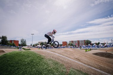Valmiera, Letonya - 12 Temmuz 2025: BMX Avrupa Şampiyonası. BMX sürücüsü havadayken toprak yolda sıçrıyor ve etrafındaki izleyiciler izliyor.