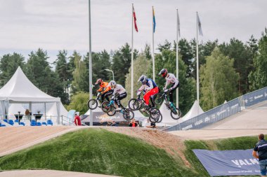 Valmiera, Letonya - 12 Temmuz 2025: BMX Avrupa Şampiyonası. BMX sürücüleri açık hava spor müsabakalarında bayraklar sallayarak yarışıyorlar.
