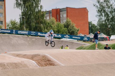 Valmiera, Letonya - 12 Temmuz 2025: BMX Avrupa Şampiyonası. Genç bir çocuk heyecan verici bir yarışma sırasında izleyicilerle BMX numaraları yapıyor.