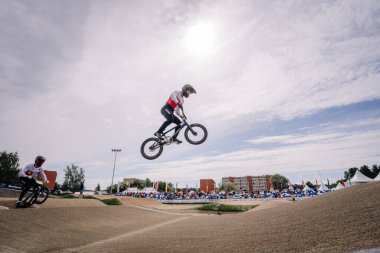 Valmiera, Letonya - 12 Temmuz 2025: BMX Avrupa Şampiyonası. BMX bisikletçisi, seyircilerle birlikte açık havada pistte bir atlayış yapıyor.