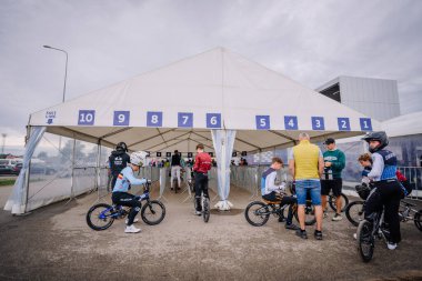 Valmiera, Letonya - 12 Temmuz 2025: BMX Avrupa Şampiyonası. BMX sürücüleri büyük bir çadırın altında numaralandırılmış şeritli bir yarışa hazırlanıyorlar.