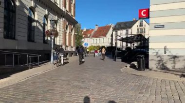 Riga, Letonya - 18 Ekim 2025: Tarihi bir bölgede büyüleyici kentsel sokak sahnesi, yayalar ve büyüleyici mimari, canlı çevreyi vurgulayan pürüzsüz bir kamera tavasıyla