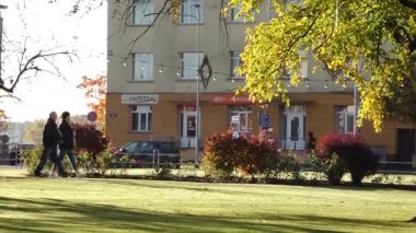 Valmiera, Letonya - 17 Ekim 2025: Erkekler canlı bir parkta sonbahar yapraklarıyla dolaşır, kamera onları pürüzsüz bir şekilde takip eder, canlı atmosferi yakalar