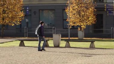 Valmiera, Letonya - 17 Ekim 2025: Asyalı erkek, canlı sonbahar yeşillikleriyle süslenmiş bir parkta geziniyor.