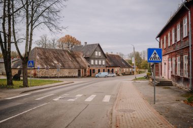 Mazsalaca, Letonya - 22 Ekim 2025: Büyüleyici köy kavşağı kırsal evler, sonbahar yaprakları ve sakin bir kaçış için huzurlu bir atmosfer içeriyor