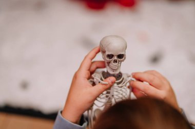 Küçük çocuk anatomik özellikleri araştıran, eğitici bir oyun oynayan, merakını arttıran ve insan anatomisini öğrenen küçük bir iskelet modeline odaklanmış durumda.