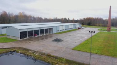 Valka, Letonya - 29 Ekim 2025: Havadan çekilen görüntüler sanayi binasını kırmızı arabalarla, kamera tavalarıyla geniş araziyi ve çevreyi gözler önüne seriyor