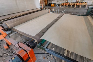 Bir imalat tesisinde endüstriyel baskı makinesinde işlenen büyük kağıt rulosu üretim akışını ve mekanizmayı iş başında gösteriyor.