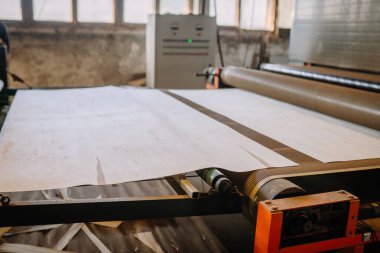 Endüstriyel atölyedeki bir baskı makinesinde büyük bir sayfa işleniyor, makineleri vurguluyor ve tasarım amaçları için yeterli kopya alanı sağlıyor